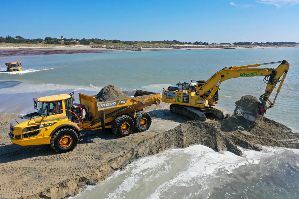 Excavatrice chargeant un camion près de l'eau